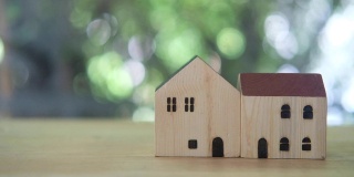 木制桌子上的微型房子模型，绿色的自然背景。房地产概念