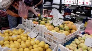 妇女在市场摊位上挑选水果，新鲜的橙子放在袋子里视频素材模板下载