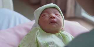 亚洲母亲看起来刚出生的男婴在医院里睡在手里