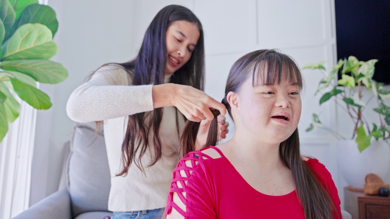 不同的姐妹为彼此做头发。一个女孩患有唐氏综合症。