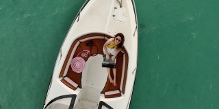一名年轻的亚洲女性游客在海上坐在一艘船上使用互联网进行交流。