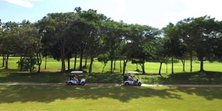 4K鸟瞰图，一群亚洲人坐在高尔夫球场的高尔夫球车上，夏日阳光明媚