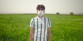 一个年轻男子的肖像与休闲服装在绿色的田野戴着防护面具。
