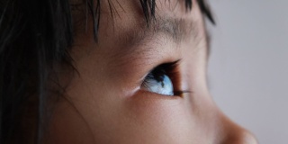 亚洲小孩仰望天空的特写。美丽的棕色眼睛，长长的睫毛。