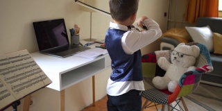 一个在家练习小提琴的男孩正在给他的泰迪熊演奏音乐