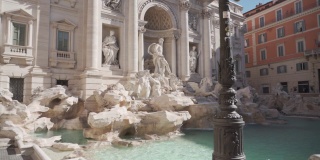 在罗马的特莱维广场，水正在流入水池的特莱维喷泉上的白色雕像。慢动作平移广角镜头