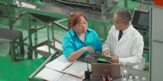 亚裔华裔女领班和经理日常在饮水厂生产线检查生产进度