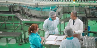 亚洲中国工厂检验员与生产线工人在日常生活中讨论饮用水工厂生产线上对矿泉水质量和生产进度的检查