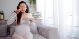 孕妇在家吃不健康的披萨。
