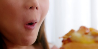孕妇在家用嘴吃不健康的披萨。