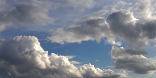 从一扇窗户看到客机开着，蓝天上飘着云朵