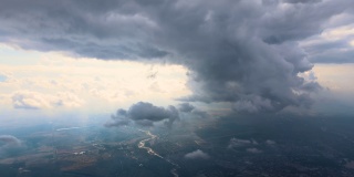从高空的飞机窗口鸟瞰，远处的城市被暴雨前形成的蓬松的积云所覆盖