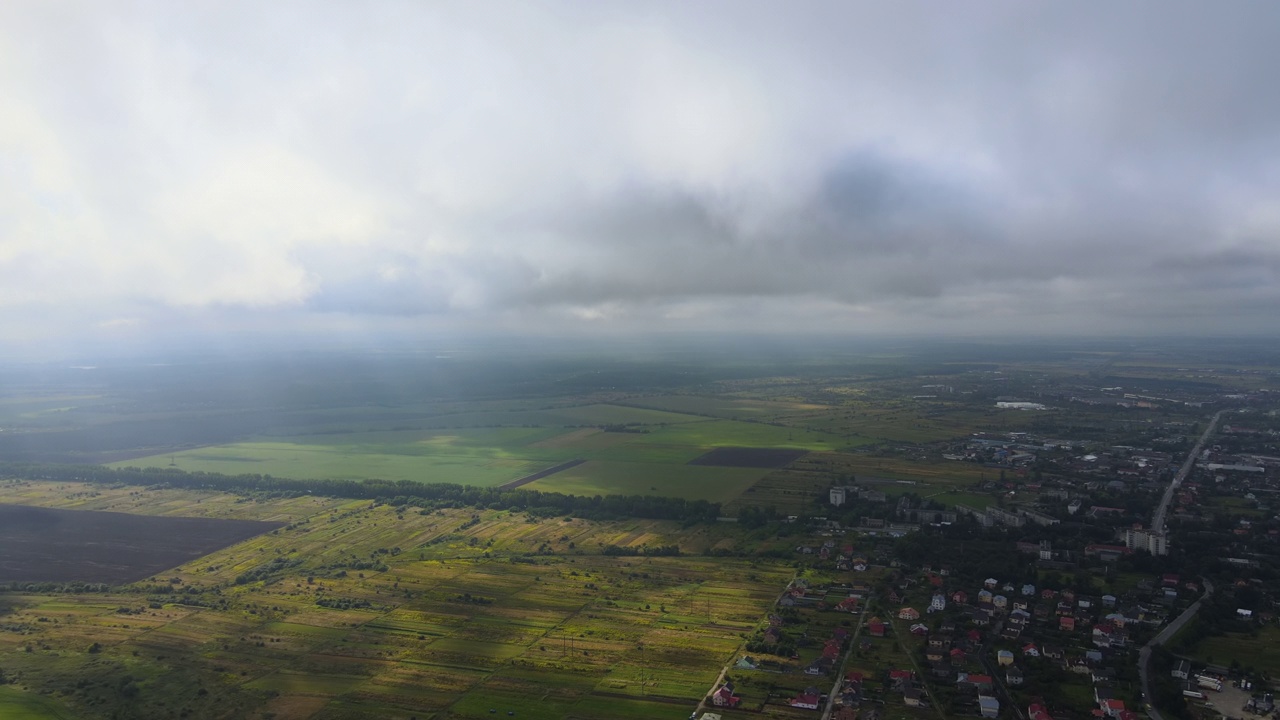 高空鸟瞰图，远处的城市被暴雨前形成的蓬松的积云所覆盖