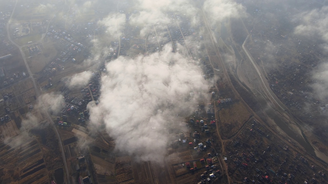 高空鸟瞰图，远处的城市被暴雨前形成的蓬松的积云所覆盖。飞机角度多云的景观