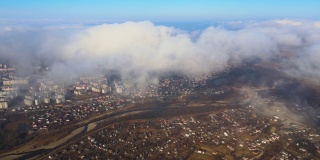 从高空俯瞰，在暴雨来临之前，蓬松的积云覆盖着遥远的城市。多云天气的飞机视角