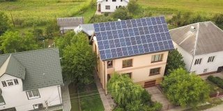 空中俯瞰新的现代住宅小屋与蓝色闪亮的太阳能光伏板系统的屋顶。可再生生态绿色能源生产理念。