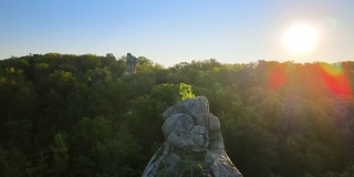 在明亮的夏日夕阳下，在黑暗的树林和巨大的岩石上，充满活力的雾蒙蒙的夜晚。黄昏时分野生森林的奇妙景色