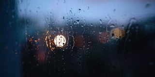 晚上，雨滴沿着玻璃流下来。窗外的城市灯火通明。拍摄特写镜头