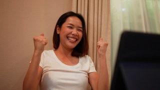 慢动作场景，成年亚洲女性在成为生活方式人概念网站每月在线彩票中奖者后，带着情绪惊喜的感觉使用数码平板电脑视频素材模板下载