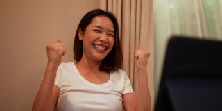 慢动作场景，成年亚洲女性在成为生活方式人概念网站每月在线彩票中奖者后，带着情绪惊喜的感觉使用数码平板电脑