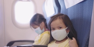 亚洲小女孩喜欢带着口罩在飞机上使用数码平板电脑