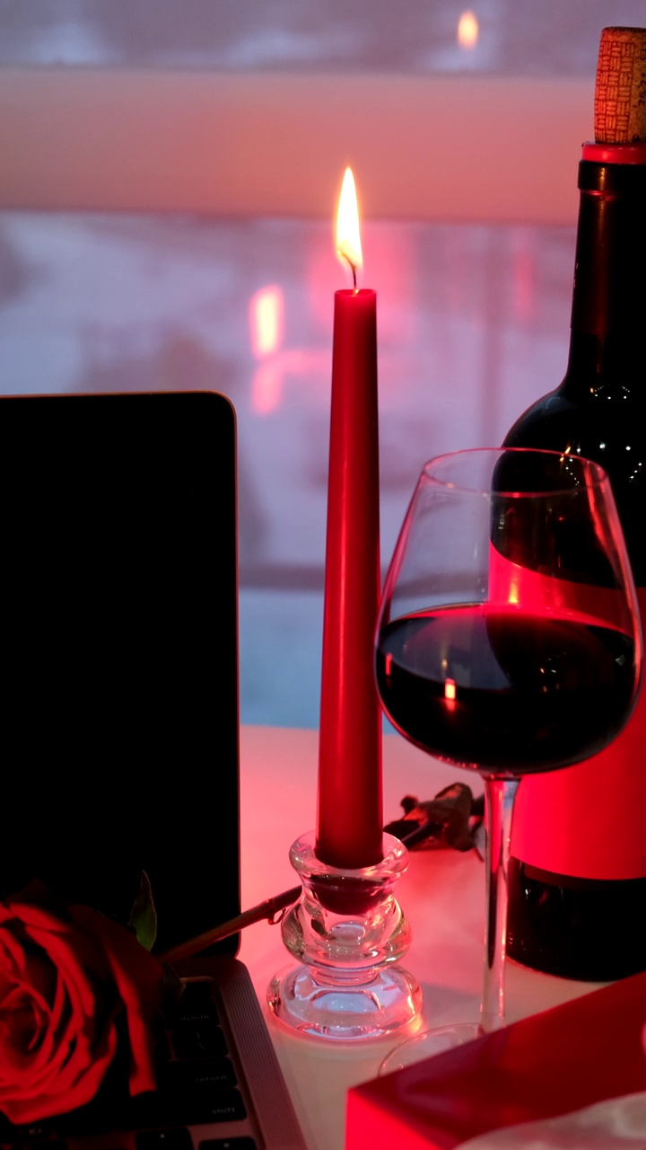 网上约会概念红蜡烛、红酒和礼物放在笔记本电脑前