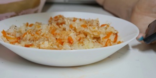 女人用叉子吃盘子里的米饭、鸡肉和蔬菜