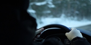 男人的手握着一辆轿车的方向盘，冬天自驾游。下雪的森林,背景。文本的复制空间
