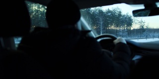 一位男性司机在寒冷的冬季夜晚开着车走在路上。冬季汽车驾驶概念，长途旅行，特写