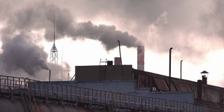 巨大的烟雾和蒸汽从工厂的烟囱里冒出来，背景是傍晚的天空，工业。制造业