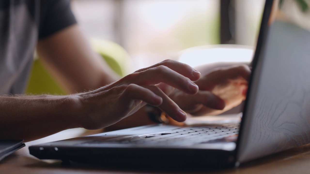 男用户双手在笔记本电脑键盘上打字坐在桌旁，商人学生专业学习工作与pc软件技术概念，近距离观看。慢动作