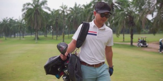 一名亚洲男子高尔夫球手步行和携带高尔夫球袋在高尔夫俱乐部