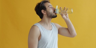 年轻的印度运动员从瓶子里喝水的慢动作肖像，然后看着相机微笑