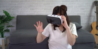 亚洲女性在家玩虚拟现实游戏，亚洲女性在假期在家快乐。快乐女人玩超时空VR技术概念。