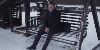 商人坐在被雪覆盖的秋千上等待会面
