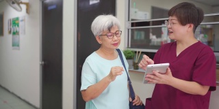 亚裔中国女护士在诊所用数码平板电脑向她的女病人解释体检报告