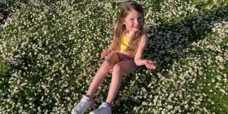 年轻的女孩在春天明媚的阳光下，在一片野花和雏菊的草地上玩耍