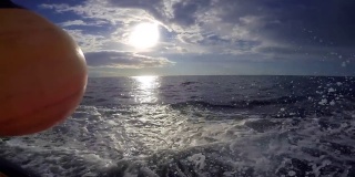 摩托艇划破深蓝色的水与太阳越过地平线