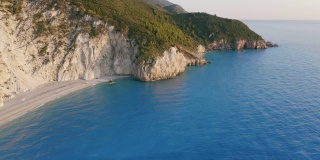 鸟瞰希腊爱奥尼亚岛莱夫卡达美丽的米洛斯海滩。悬崖海岸在夕阳金色的阳光和蓝绿色的海湾