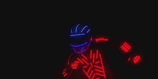 男人穿着发光二极管的服装和彩色的灯跳舞和移动在黑暗的室内或俱乐部。跳舞的人穿着身上有霓虹灯的衣服跳舞。用ARRI相机拍摄