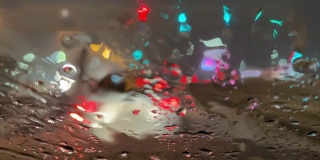 潮湿的道路上，汽车行驶在夜晚的冬季街道上。雨雪落在汽车的挡风玻璃上。在恶劣天气，车辆行驶在潮湿、多雨、湿滑的道路上