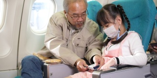 爷爷在飞机上为他的孙女系安全带，旅行和度假的概念