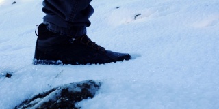 从侧面看，一个人走在雪地上的脚