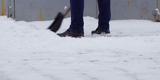 一个人用铲子铲雪。消除降雪的后果。