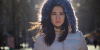 年轻女子的肖像，在温暖的衣服站在城市的街道在阳光明媚的冬日