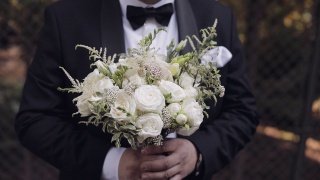 新郎手捧婚礼花束在户外准备去娶新娘，特写镜头慢动作视频素材模板下载