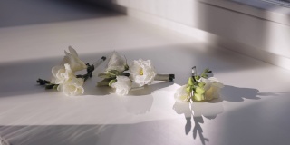 三名婚礼伴娘的白色花束躺在窗台上，在阳光的背光下