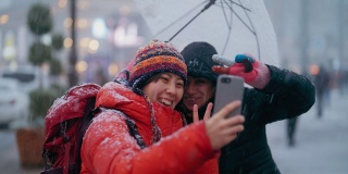 冬天的城市里，年轻的女游客用智能手机和当地人自拍