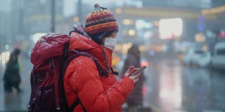 冬天，年轻的女游客在城市里用智能手机等待红绿灯