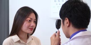 验光师使用视网膜镜和主观折射测试亚洲年轻女性的视力，准备配眼镜，表达积极的情绪，微笑以获得更好的视力